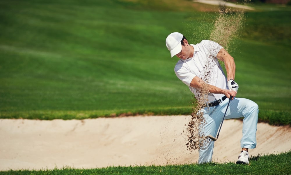 Golfer playing shot out of bunker