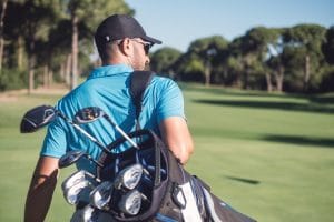 Golfer carrying golf clubs in a bag