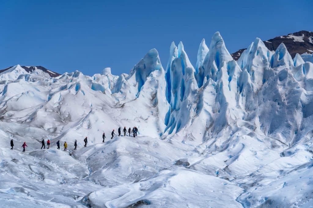 People walking in line on a glacier