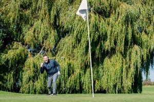 Golfer celebrating as he ball drops in to the hole