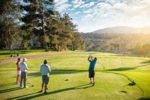 A man teeing off as his friends watch him