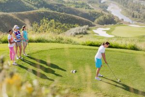 Female golfer teeing off while friends watch