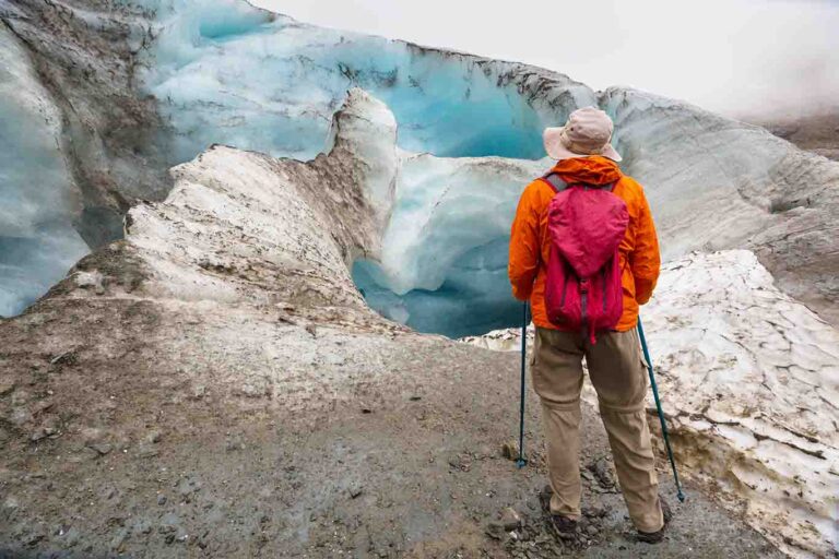 man hiking beside glacier ice