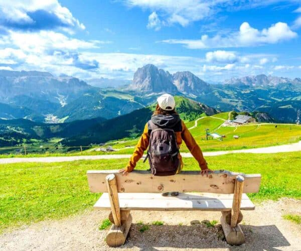 hiker on bench admiring the view in the mountains