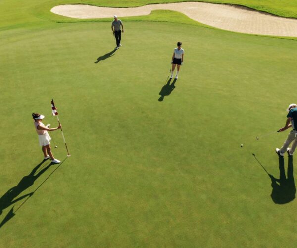 Aerial view of golf group with one golfer playing putting for the hole