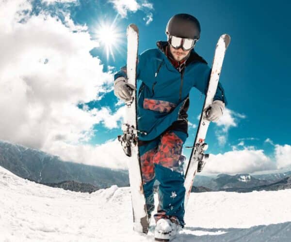 Male skier holding skis dressed in ski gear
