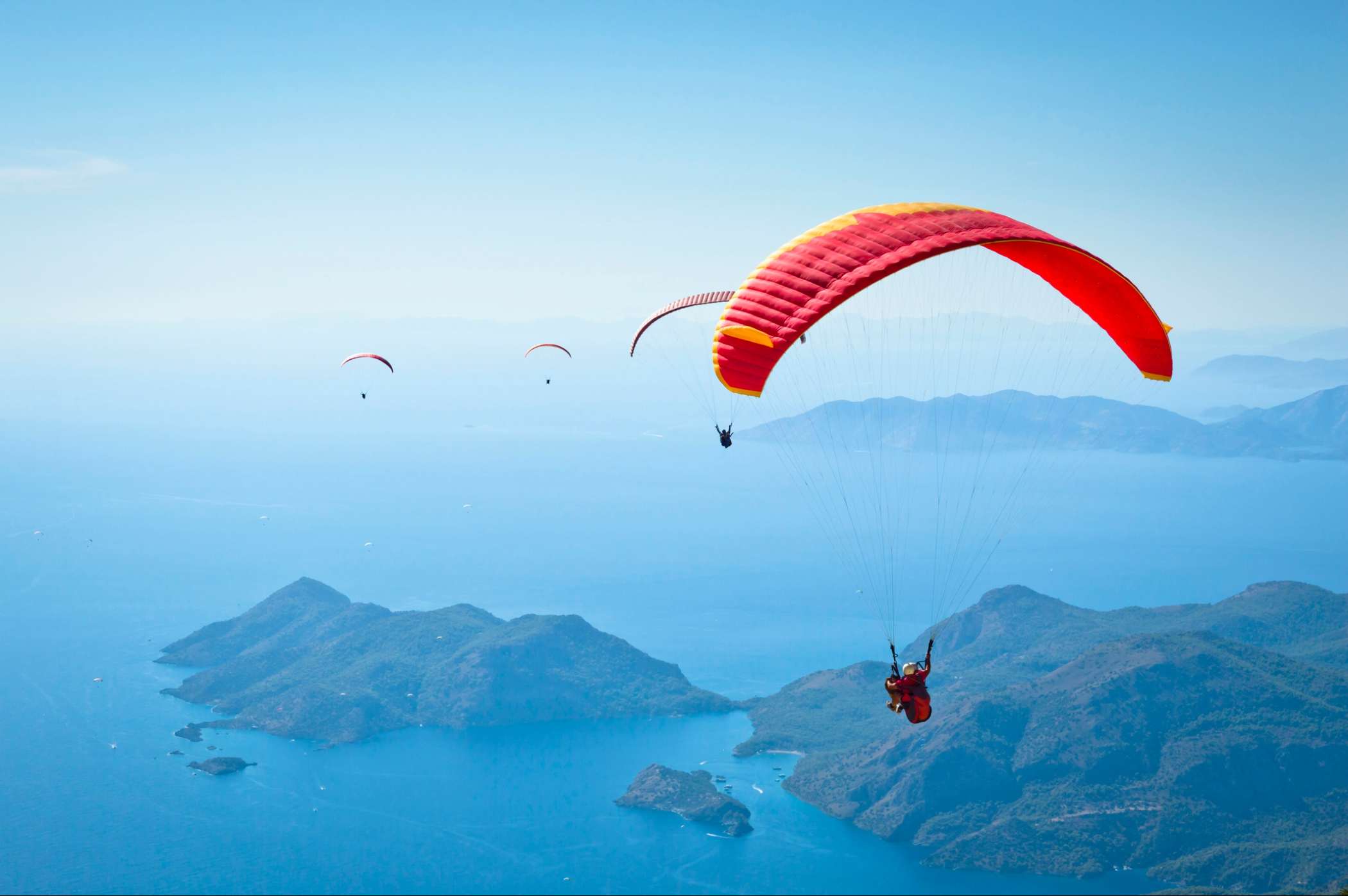 Paragliders flying over islands and sea