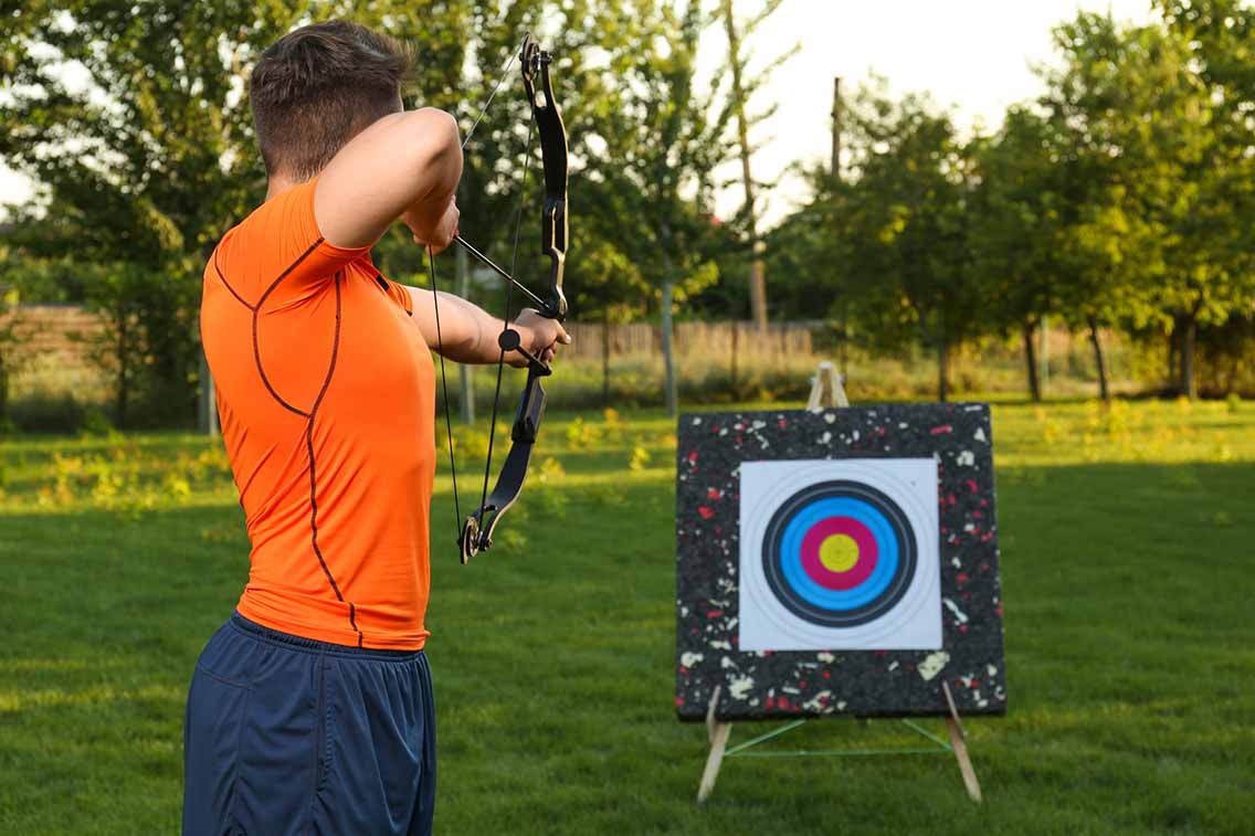 Man taking aim at archery board