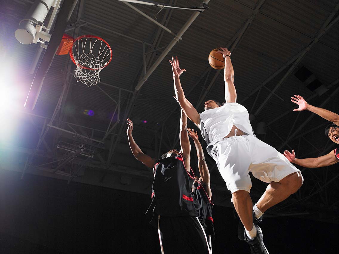 Basketball players jumping to shoot and defend