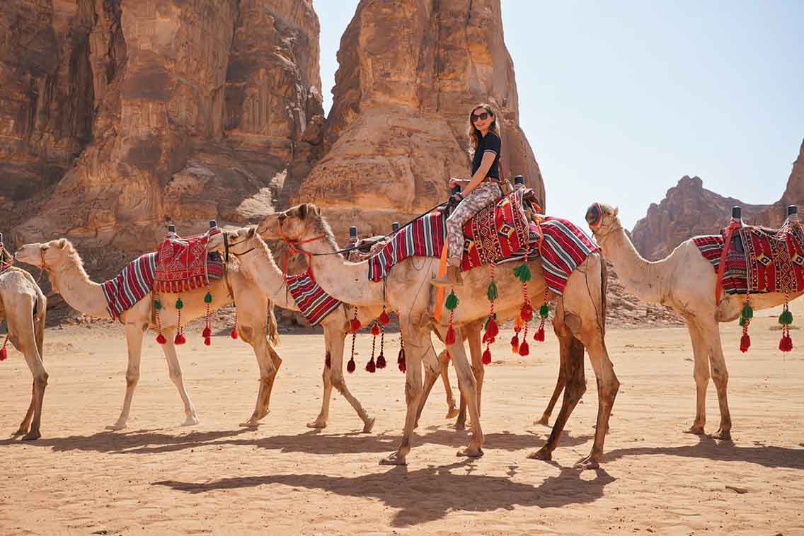 Woman on camel beside other camels