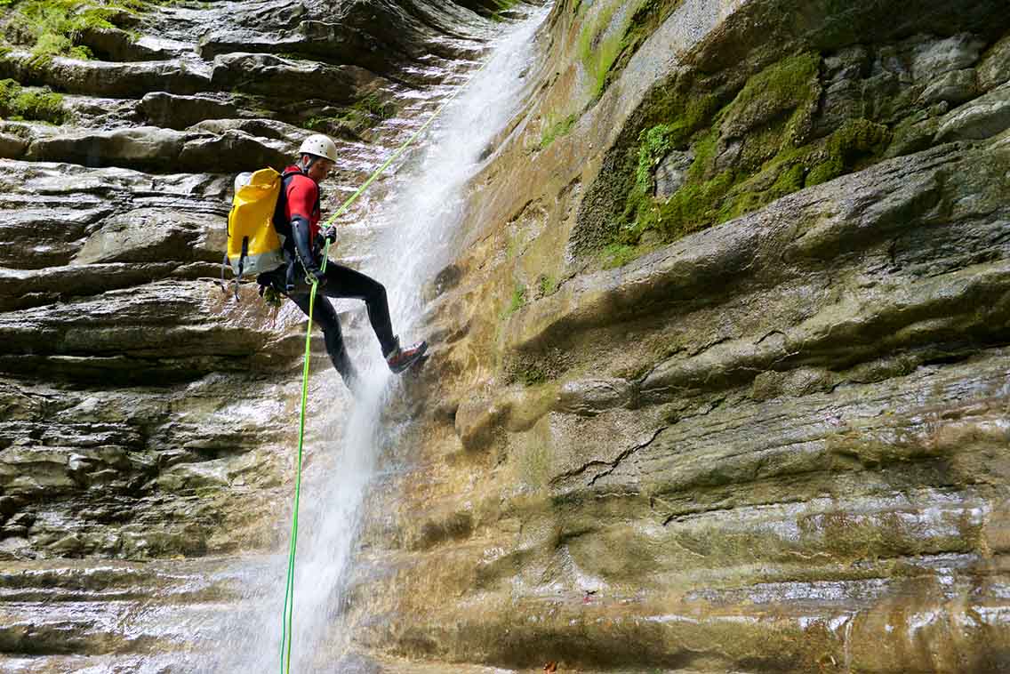 Man abeiling down canyon waterfall