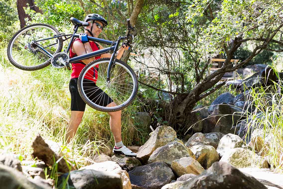 Man carrying bike across rough terrain