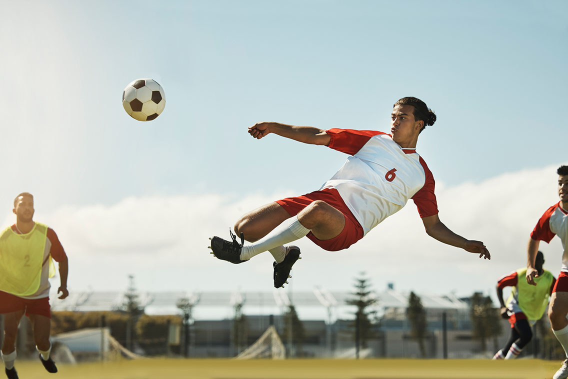 Football player kicking ball mid-air