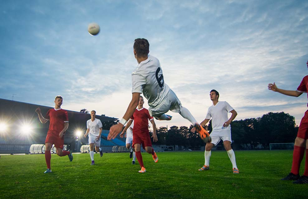 Football player kicking mid-air with team