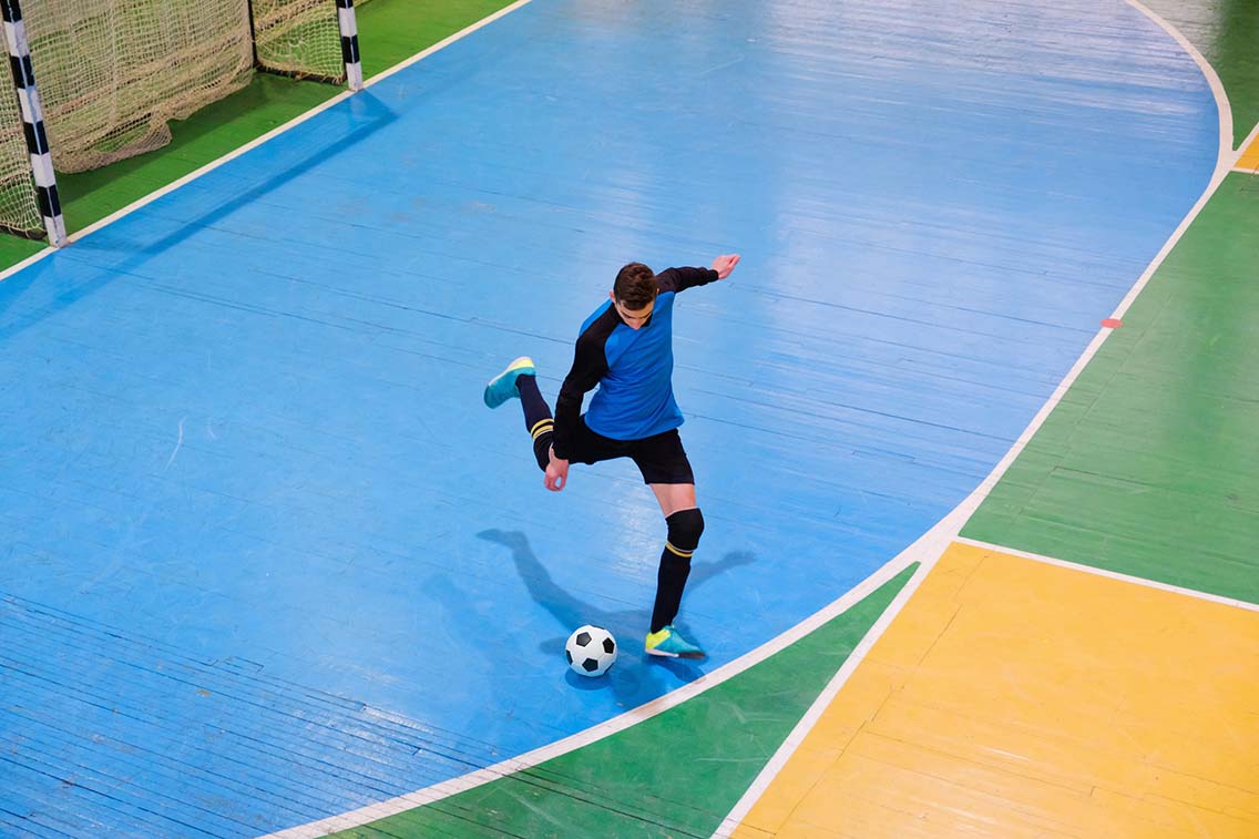 Futsal player kicking ball on indoor court