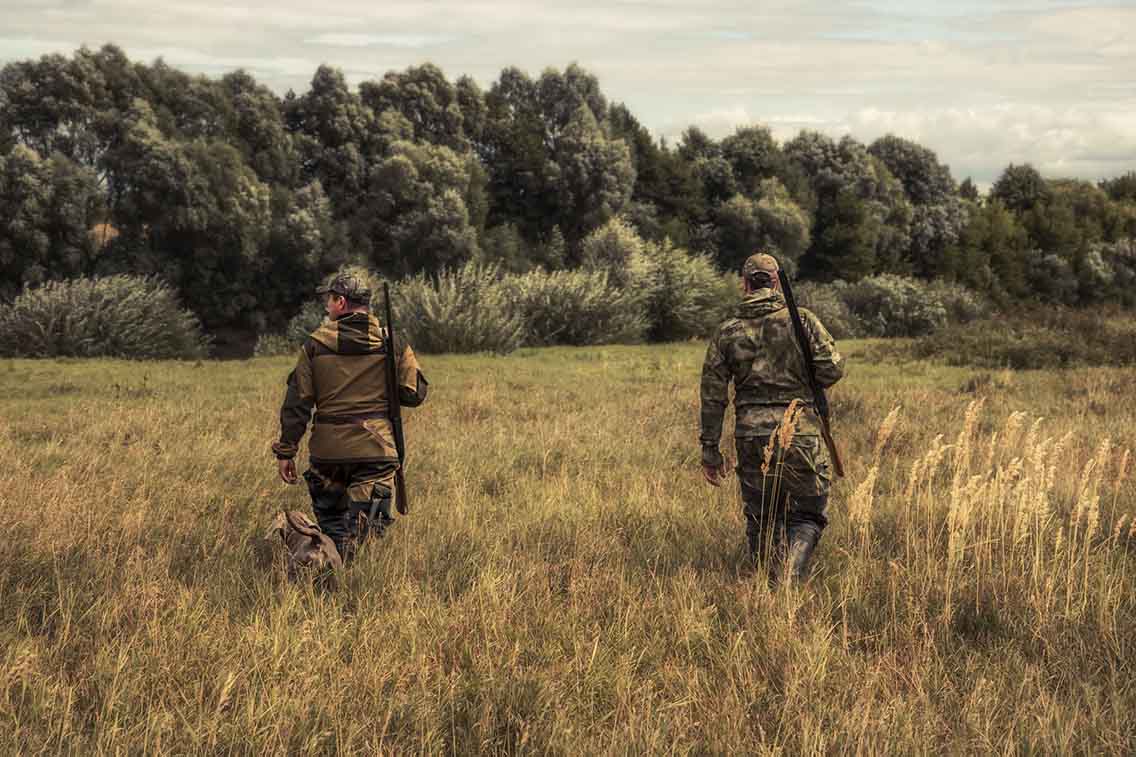 2 hunters in camoflauge clothes in field