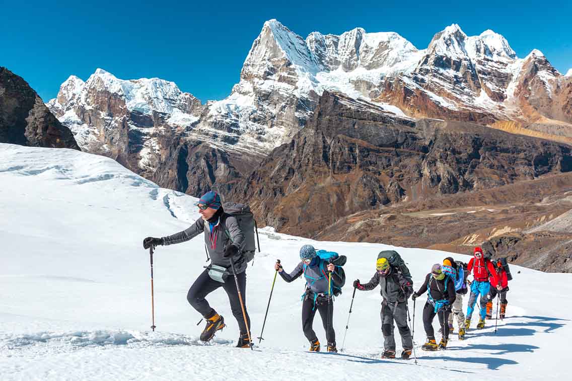 Group hiking on glacier with mountain backdrop