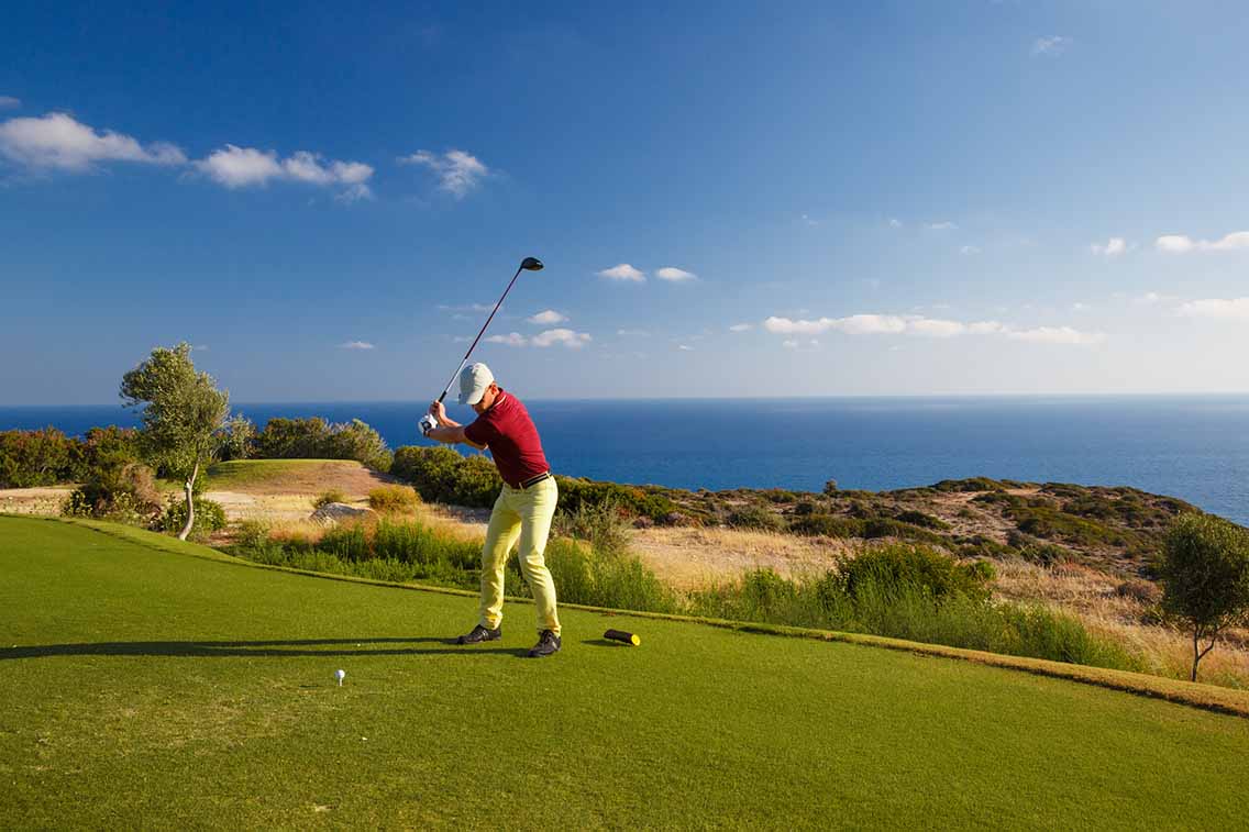 Man preparing golf shot with sea view