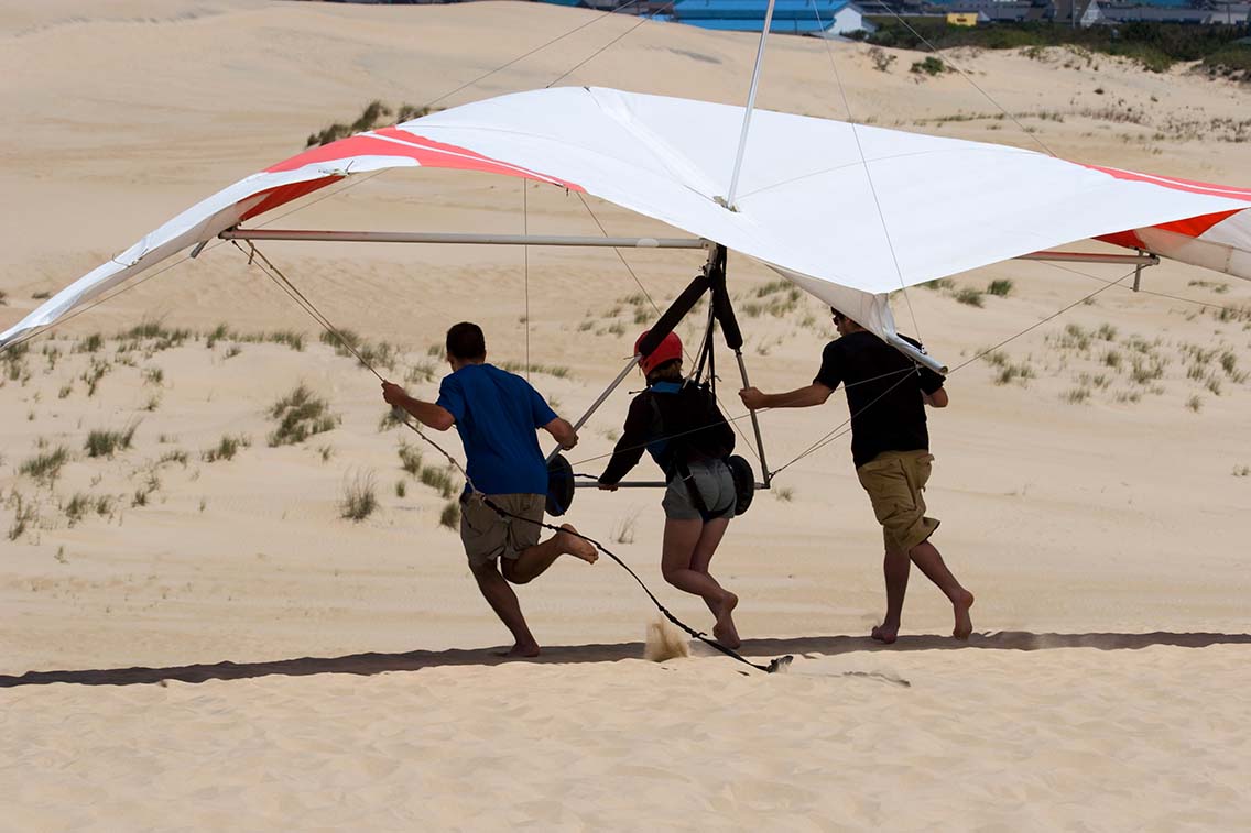 3 person hang glider with people taking off
