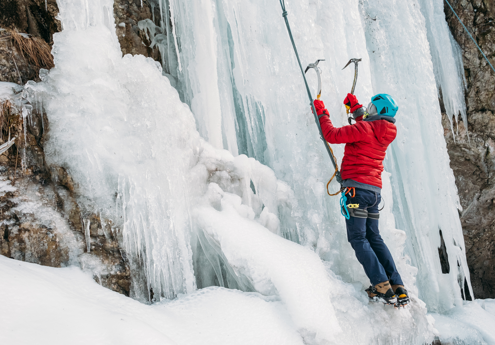 Ice climber with grappling hooks into ice