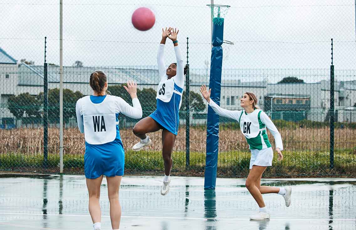 Woman shooting netball with defenders