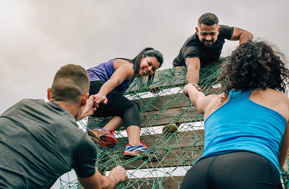 Group helping each other over obstacle wall