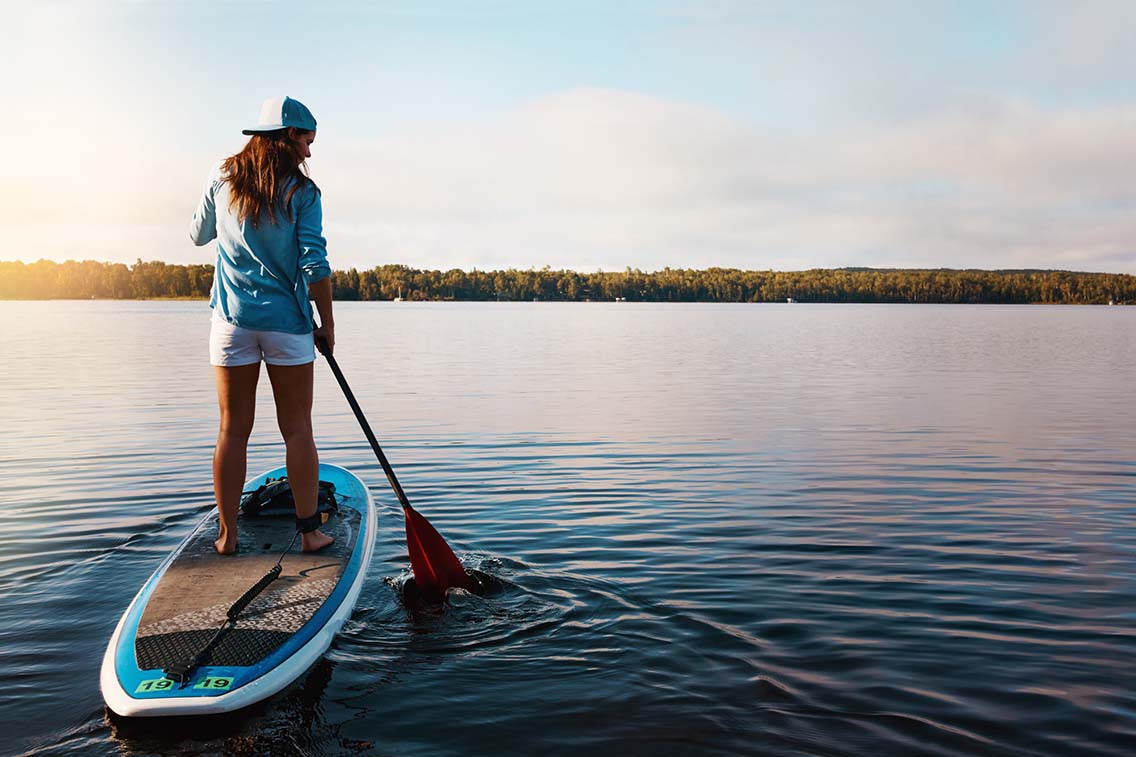 Woman paddleboarding on still lake