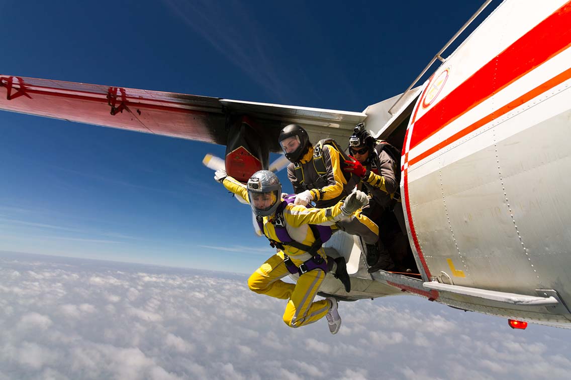 2 women jumping out of plane with parachutes