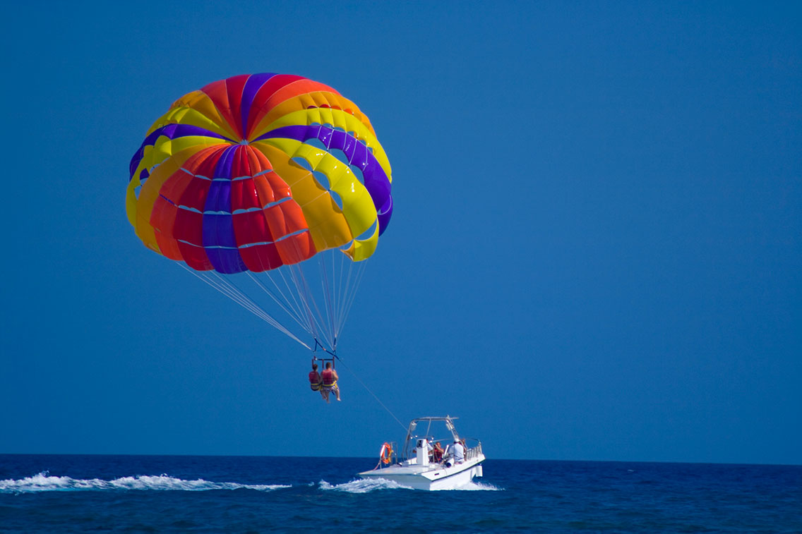 2 people parasailing behind boat at sea