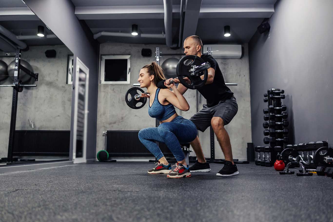 Personal trainer with client doing weights