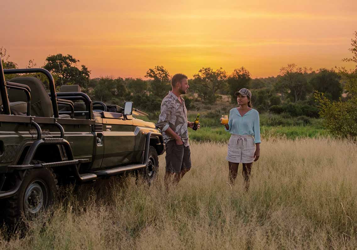Man and woman in safari terrain with safari vehicle