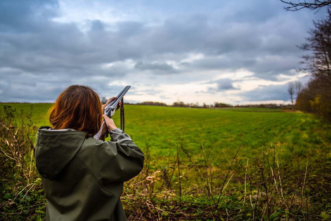 Woman with shotgun in field