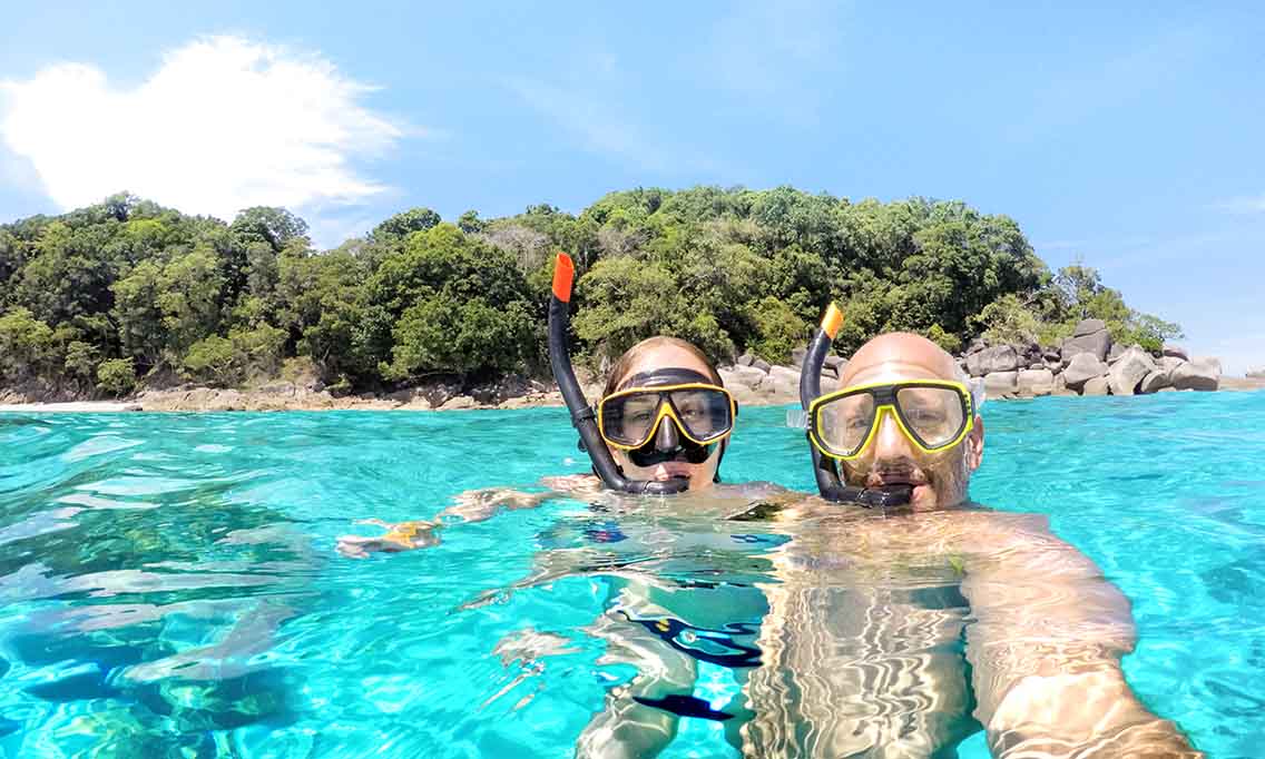 Man and woman with snorkels in bright blue sea