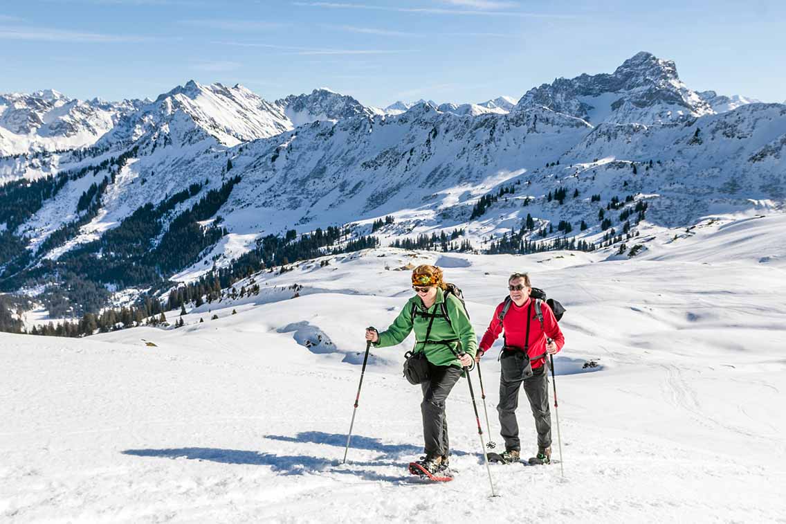 Man and woman snow shoeing on snow covered terrain