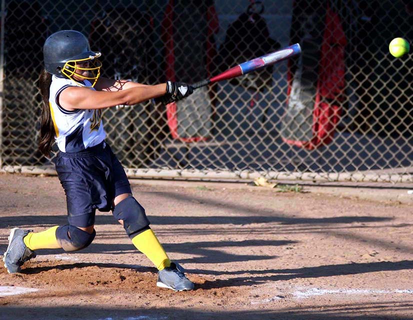 Softball player hitting ball