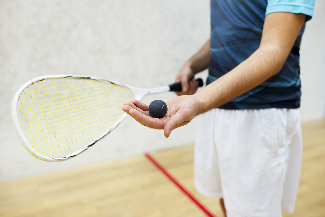 Squash player holding racket and ball