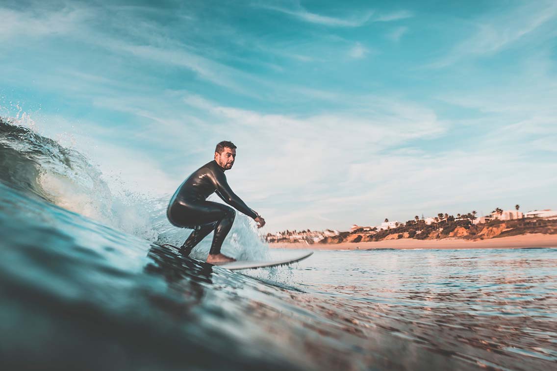 Man surfing wave with coastal background