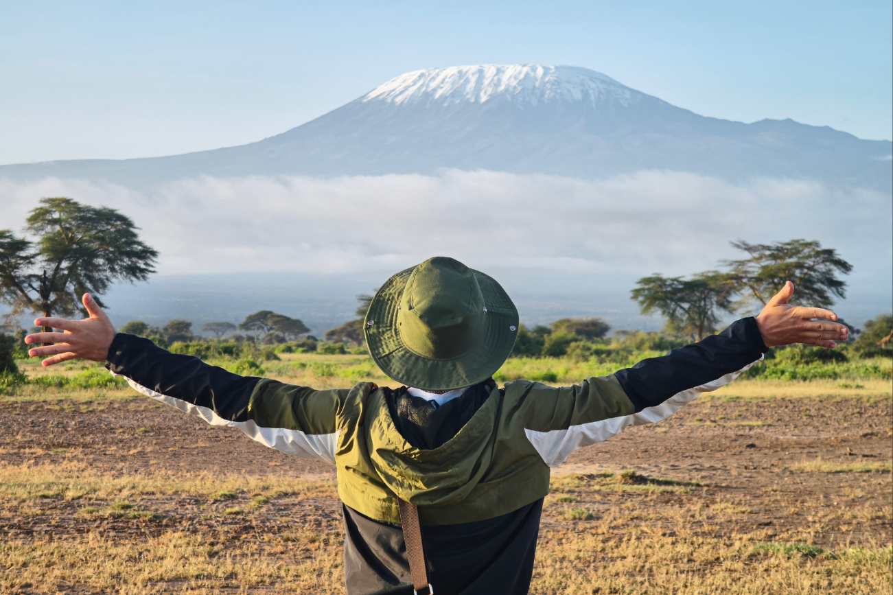 Man in hikinhg gear looking at Mt Kilimanjaro