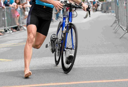 runner is running near his bicycle at triathlon