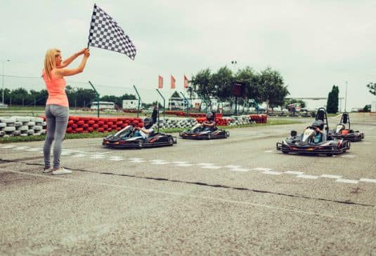 Go Karting – Benefits r Woman with a flag before go karts start the race