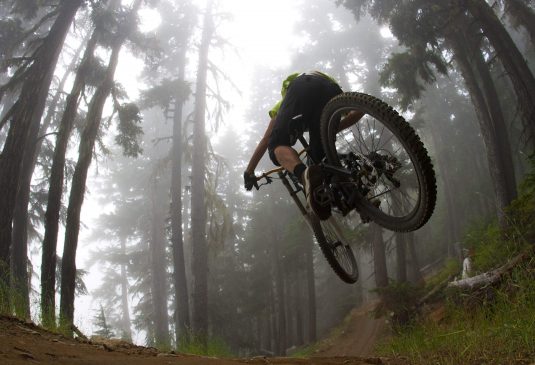 Morzine Mountain Biking c Mountain biker jumping in forest