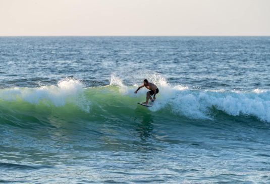 Surfer riding waves in Furadouro Beach Surfer riding waves in Furadouro Beach, Portugal. Men catching waves in ocean. Surfing action water board sport. people water sport lessons and beach swimming activity on summer vacation.