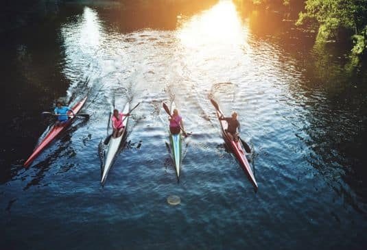 Team of rowing people sailing in sunset