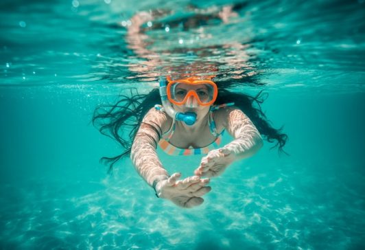 Underwater view of beautiful woman swimming in blue ocean water