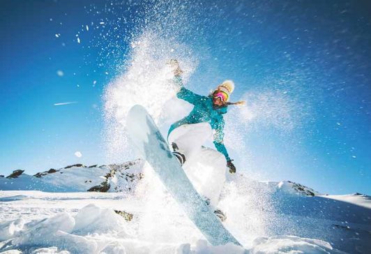 Woman jumping on a snowboard