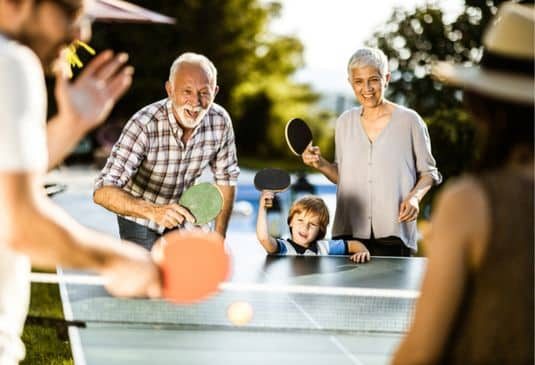 Family having fun while playing table tennis in the backyard.