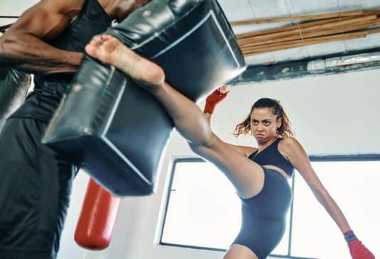 Female kickboxer practicing with her trainer