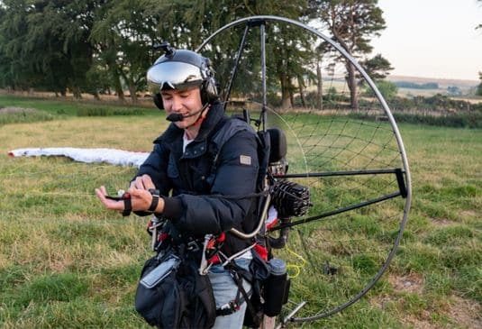 Man making last minute checks, as he prepares for take-off on his paramotor