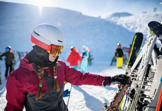 Teenage girl is reaching for her ski left at the ski stand