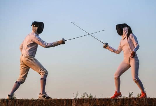 Female and male fencers fighting